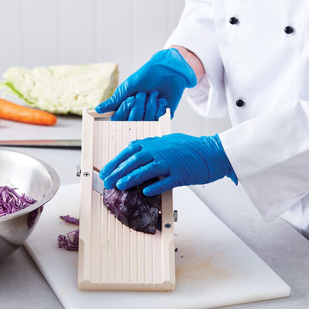 Man cutting vegetables wearing powder free blue prep gloves